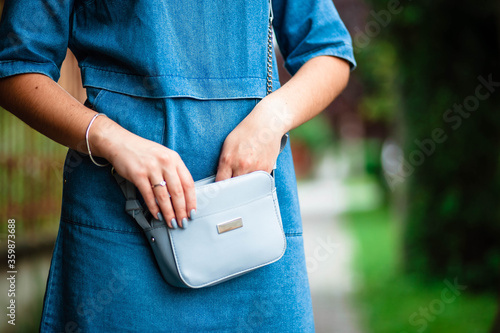 Woman's hand keeping her smartphone in her handbag while. Selective focus. Handbag. Bag in women's hands.