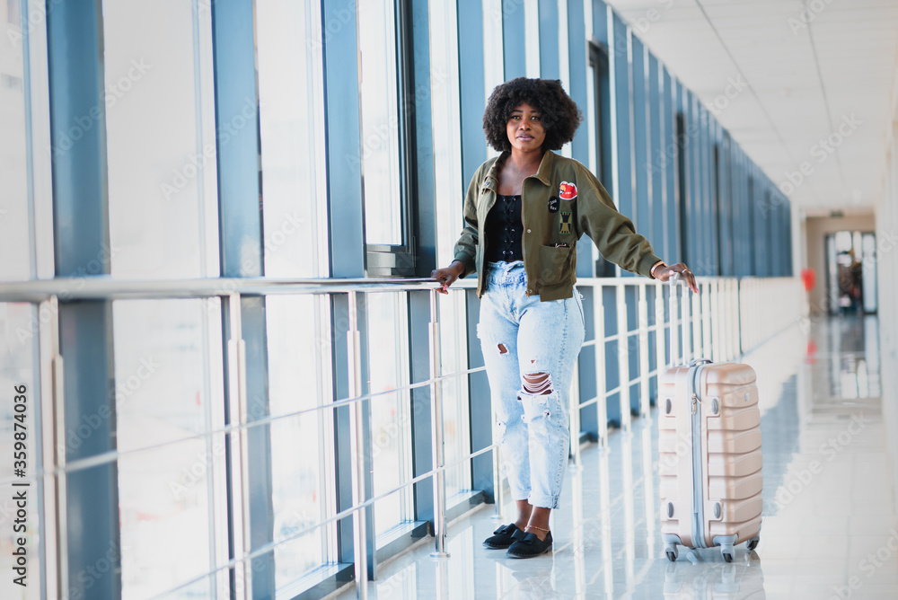 Full length side portrait of young black woman walking with suitcase in airport Full length side portrait of young black woman walking with suitcase in airport