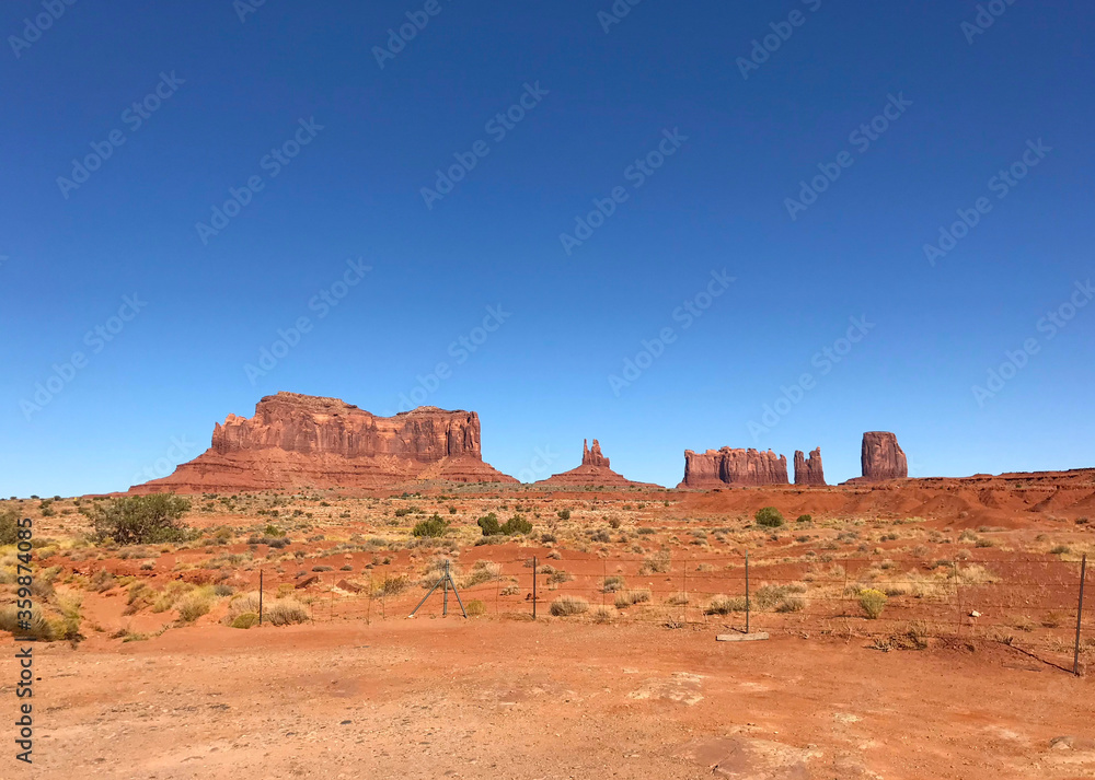 Amazing view of Monument Valley with red desert and blue sky and clouds in the morning. Monument Valley in Arizona with West Mitten Butte, East Mitten Butte, and Merrick Butte.	