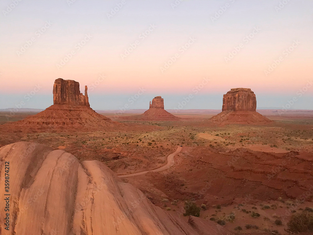 Amazing view of Monument Valley with red desert and blue sky and clouds in the morning. Monument Valley in Arizona with West Mitten Butte, East Mitten Butte, and Merrick Butte.	