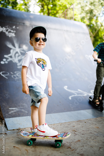 Boy with a skate in a skate park. A boy with glasses learns to skate.