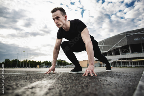 Man at the start, getting ready to run. Young athlete man running near the stadium. The man trains outdoors. Preparing for the marathon