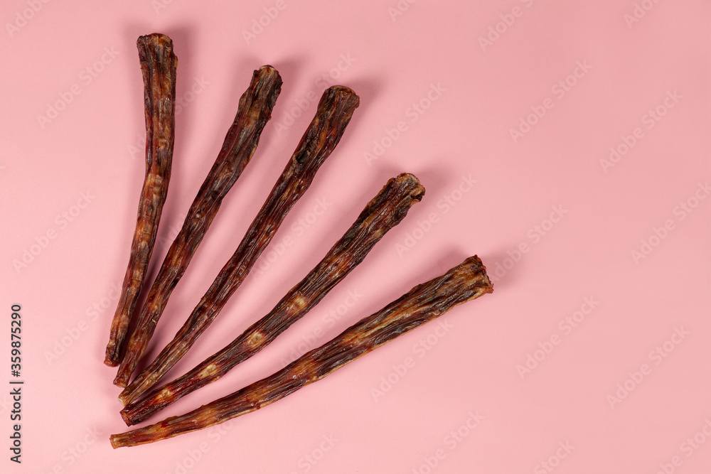Some dry beef tails on pink background. Dehydrated dog treats, crunchy meat and bones. Homemade pet food, healthy and natural. Big copy space for any text. Some dry beef tails on pink background. Dehydrated dog treats, crunchy meat and bones. Homemade pet food, healthy and natural. Big copy space for any text.