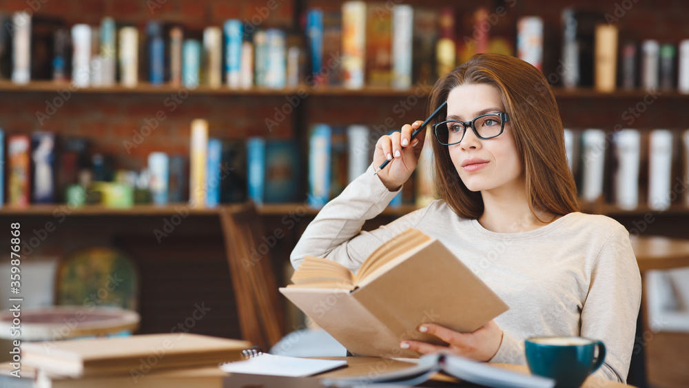 Young girl in glasses reading book and enjoying coffee time Young girl in glasses reading book and enjoying coffee time