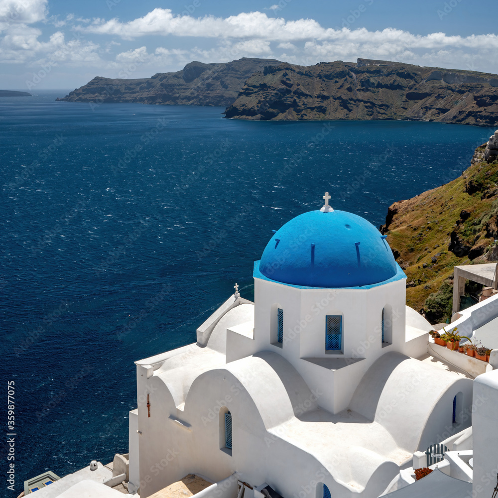Santorini blue domed church overlooking the Mediterranean Aegean Sea and caldera on a sunny blue sky day