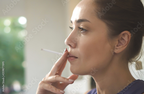 Woman enjoying her cigarette in the morning outdoors. Girl smoking a cigarette close up