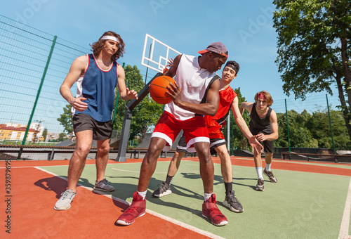 Male basketball team training for championship at outdoor court © Prostock-studio