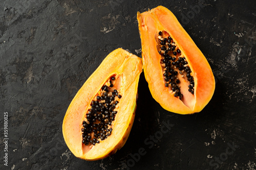 FFresh and tasty papaya cut in half on a black texture background. Copy of space photo