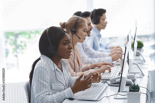 Tableau sur toile Stressed call center manager with headset listening to clients complaint and her