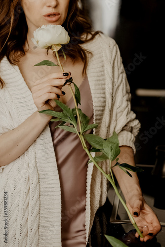 Young attractine woman holds white peony flower in her hand photo