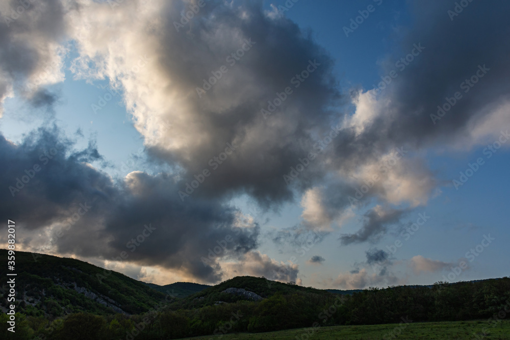Storm clouds over the forest. Spring landscape with large clouds. Before the rain. Rural landscape. Deciduous forest and green meadow. Not an urban landscape scene.