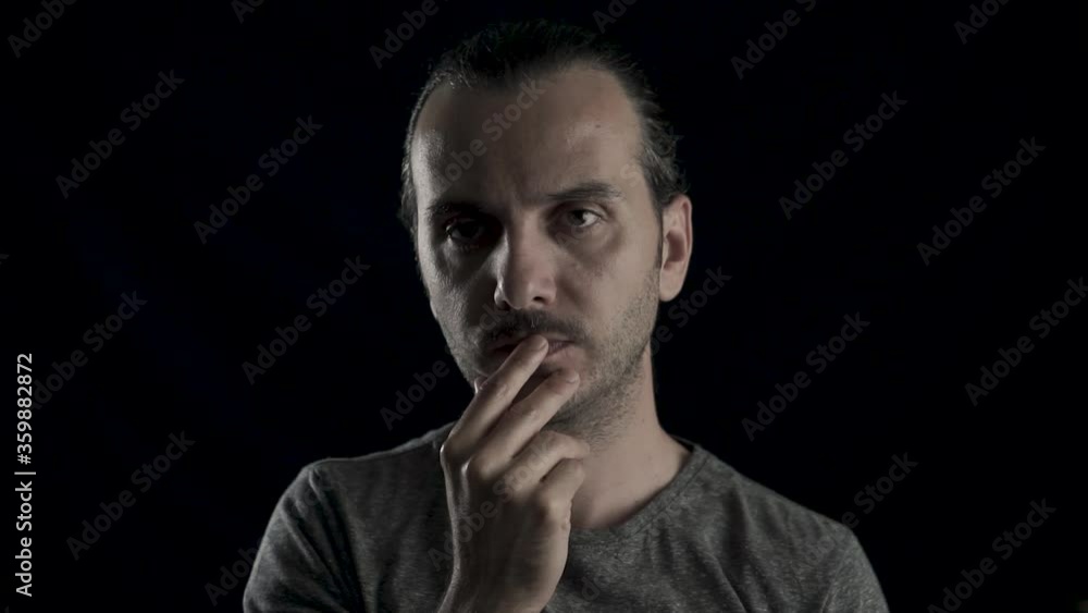 Thoughtful man's face portrait in studio, black background. Young handsome cool guy in doubt. Thoughtful man's face portrait in studio, black background. Young handsome cool guy in doubt.