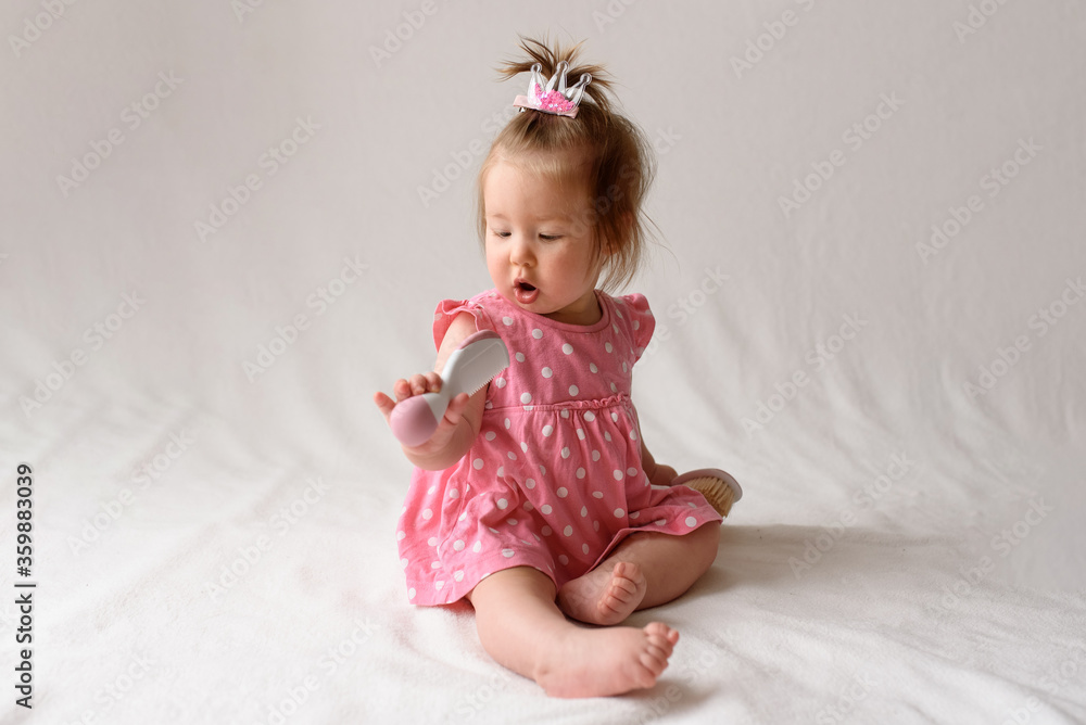Little girl 6 months old with a comb in hand on a white background. Little girl 6 months old with a comb in hand on a white background.