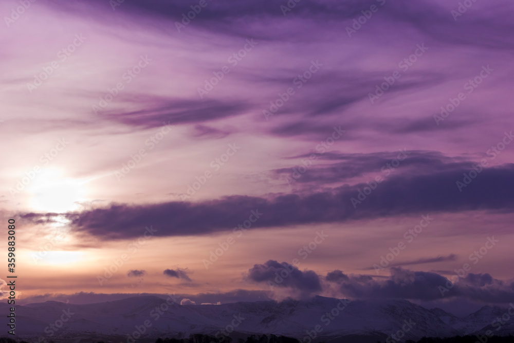 Colourful morning winter sunrise behind the snow-capped peaks of the Snowdonia Mountain Range in North Wales Colourful morning winter sunrise behind the snow-capped peaks of the Snowdonia Mountain Range in North Wales