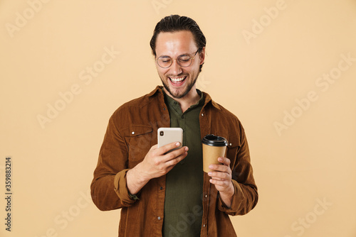 Image of cheerful man drinking coffee takeaway and using cellphone © Drobot Dean