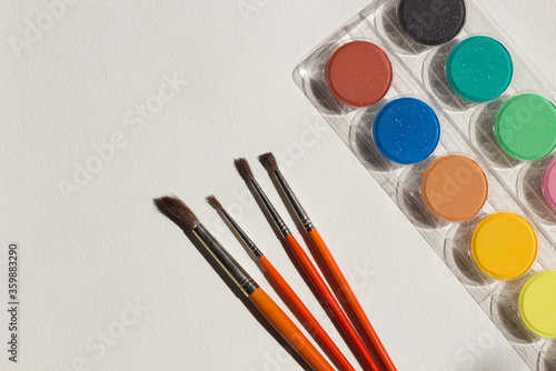 Art equipment: paint and brushes on white paper background