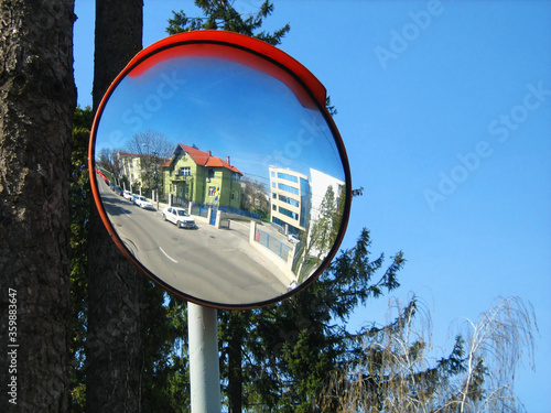 Round convex traffic mirror on the alley for better visibility. Convex mirrors provide a wider field of view on roads, driveways and in alleys.