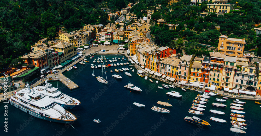 Aerial view of sea bay with beautiful picturesque village called Portofino. .Small marina port with moored boats and yachts at the foot of mountain with a beautiful colourful houses village
