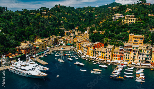 Aerial view of sea bay with beautiful picturesque village called Portofino. .Small marina port with moored boats and yachts at the foot of mountain with a beautiful colourful houses village