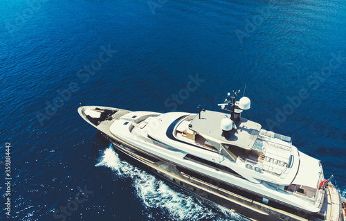 Aerial view of luxury yacht goes to open sea with beautiful blue colour of water. Wealth recreation lifestyle. Bird's eye view of expensive floating ship traveling by Europe in summer © BullRun