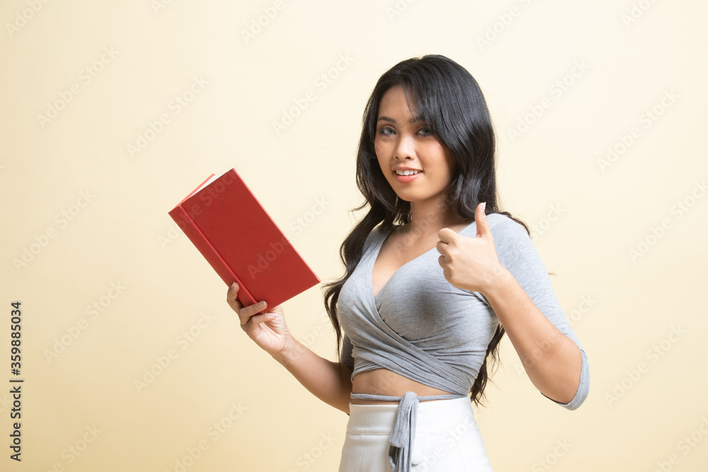 Young Asian woman thumbs up with a book. Young Asian woman thumbs up with a book.
