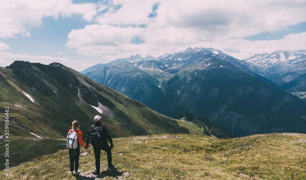 Romantic couple of backpackers standing on mountain top and enjoying beauty of nature during vacations. Man and woman wanderlusts with rucksacks exploring scenery places traveling in National Parks