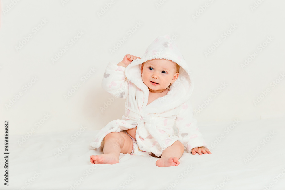 Baby in a bathrobe after bathing sits on a bed Baby in a bathrobe after bathing sits on a bed