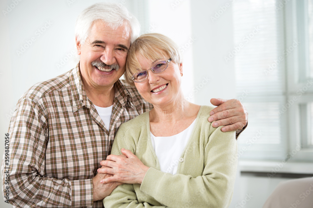 Happy elderly couple hugging at home and smiling Happy elderly couple hugging at home and smiling