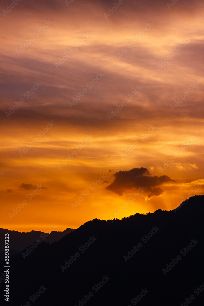 Sunset colours in sky over a mountain in silhouette