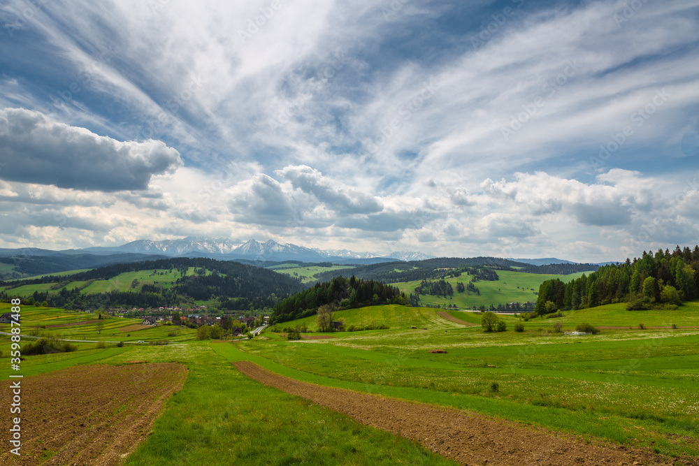 Fototapeta premium Spring in the Tatra Mountains. Green fields against the backdrop of snowy peaks. Landscape photo from Lesser Poland.