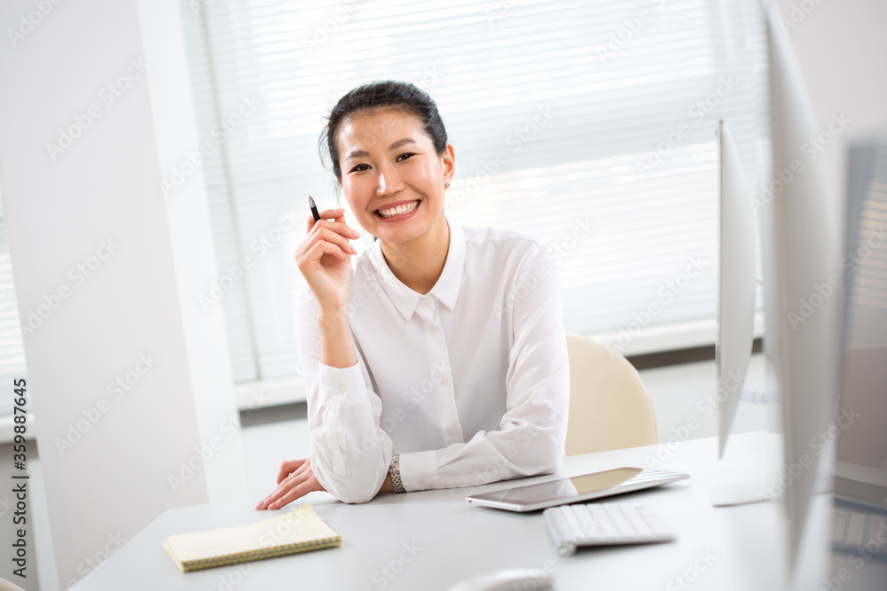 Asian business woman smiling at camera in an office Asian business woman smiling at camera in an office