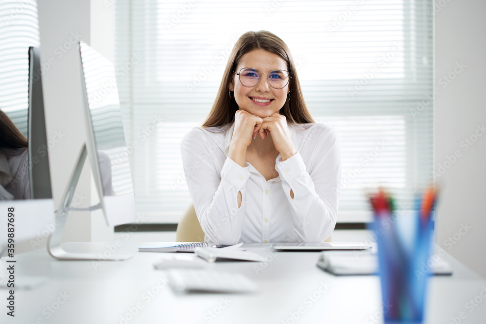 Portrait of business woman looking at camera at workplace in an office Portrait of business woman looking at camera at workplace in an office