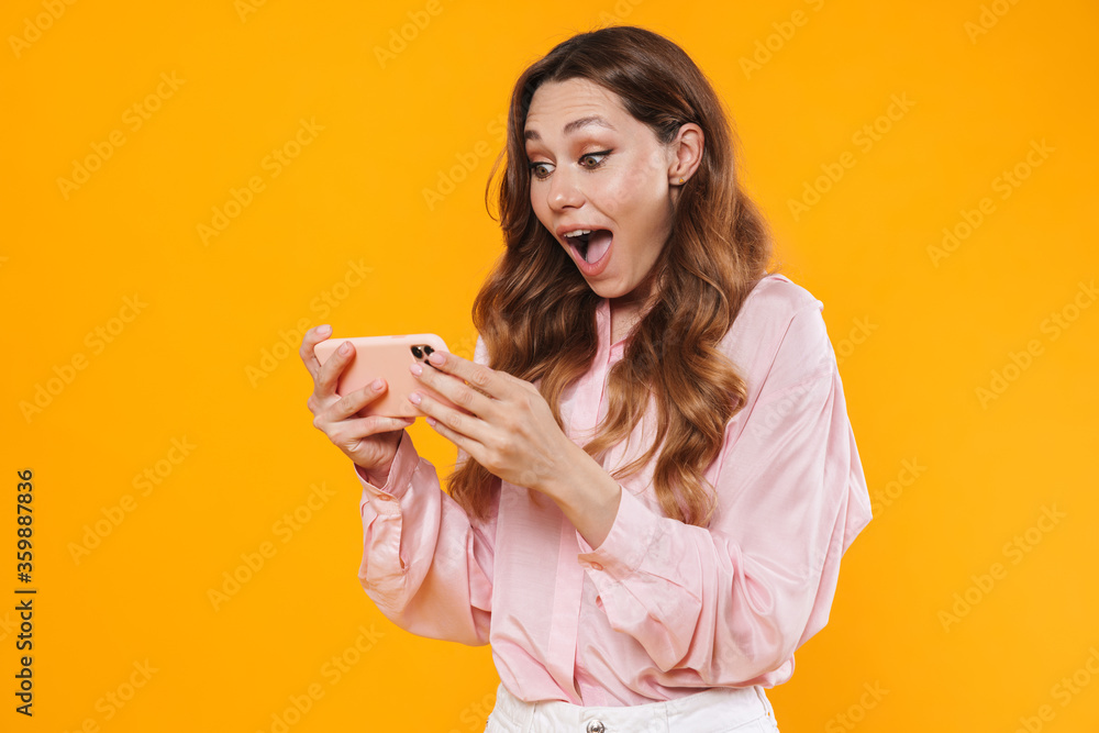 Image of delighted woman expressing surprise and using mobile phone Image of delighted woman expressing surprise and using mobile phone