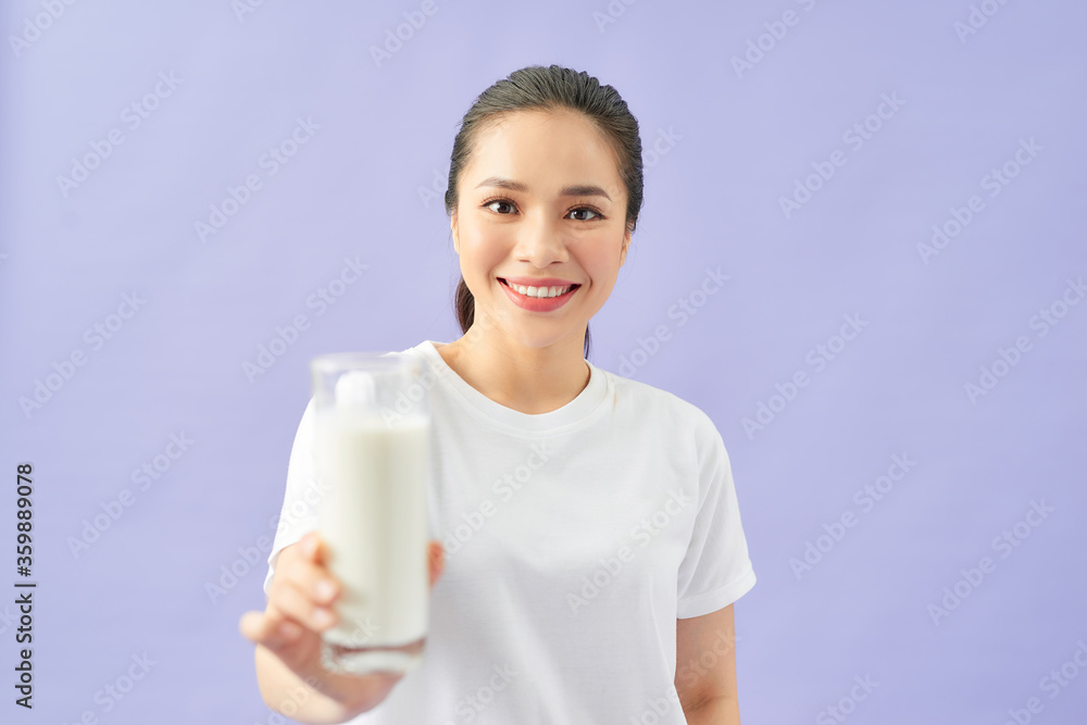 Beautiful asian woman shows a glass of milk, isolated over purple background. Milk and commercial concept. Beautiful asian woman shows a glass of milk, isolated over purple background. Milk and commercial concept.