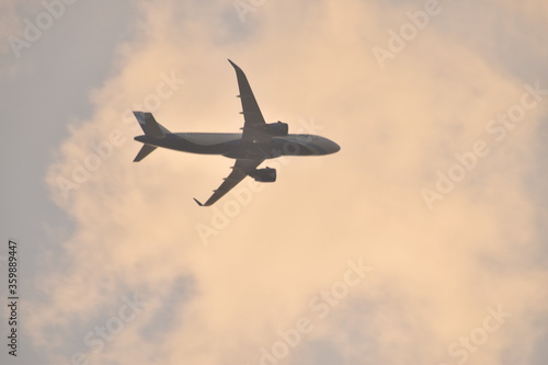 an air plain taking off in the clouds during sunset in india.