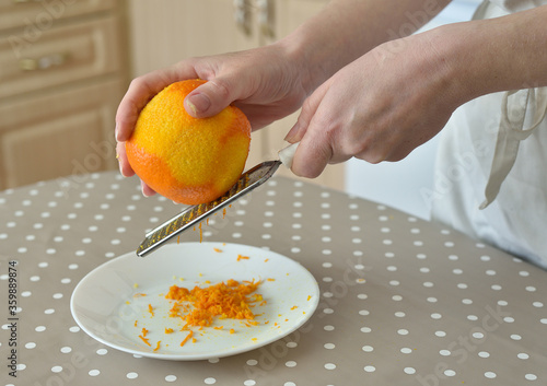 Closeup of woman rubbing orange zest on grater
