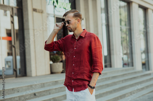 Young man in sunglasses stands on street.