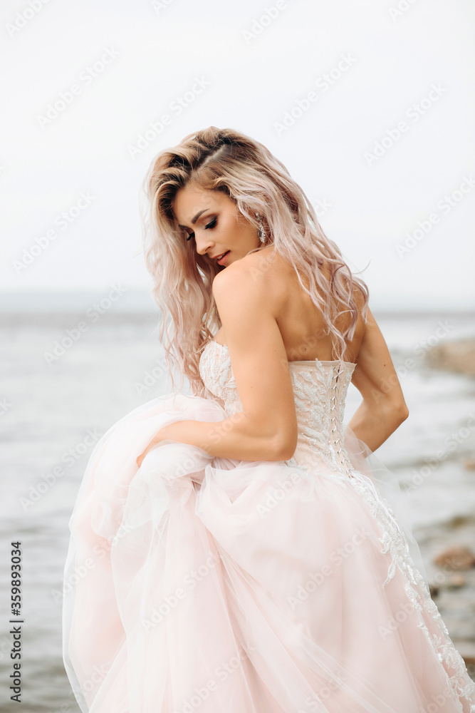 portrait of a sexy bride in water . A girl with loose hair in a soft pink dress, against the background of the sea. portrait of a sexy bride in water . A girl with loose hair in a soft pink dress, against the background of the sea.