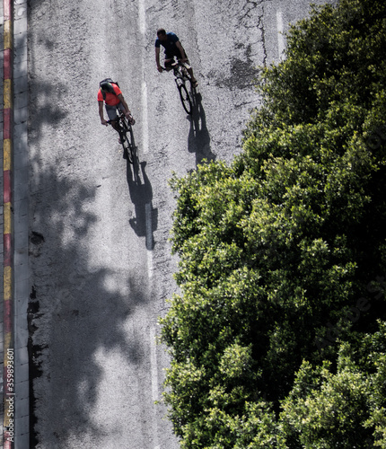 Isolated close up top view of an urban street with bicycle riders casting big shadows- TLV- Central Tel Aviv Israel photo