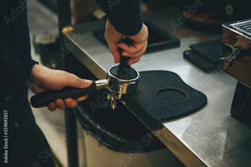 Barista presses ground coffee