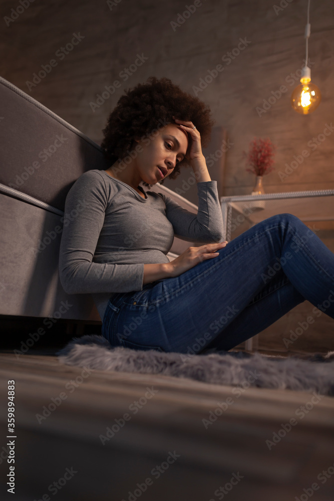 Stressed out woman sitting by the bed at night