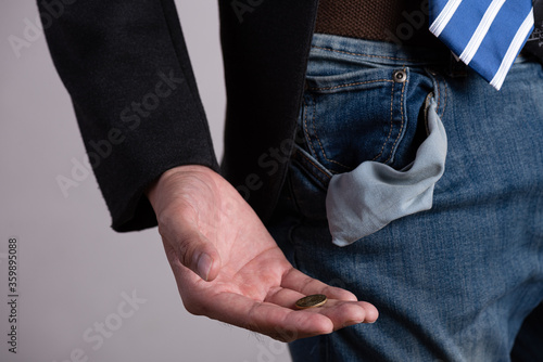 Coins in hand with empty pocket. A young businessman in a business suit showing his empty pockets. Financial difficulties, bad economy, no money concept. © Siam