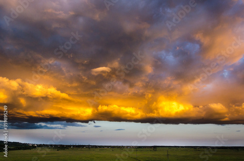 A large Cumulus cloud, illuminated by the setting sun, hovered over a green field.