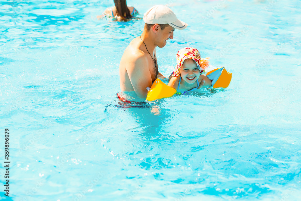 Father playing with his daughter in swimming pool