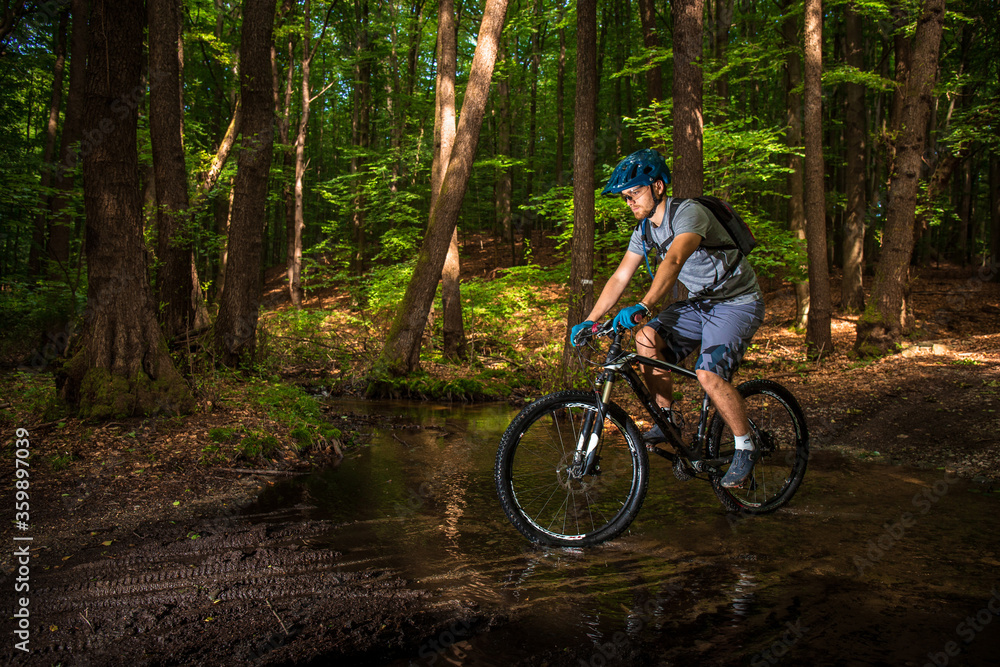 Guy riding on a bicycle in a puddle in the woods