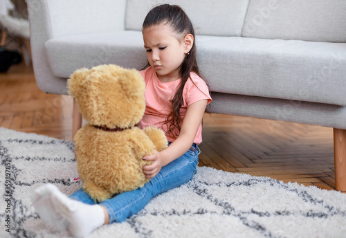 Depressed Kid Girl Holding Teddy Bear Sitting Alone At Home