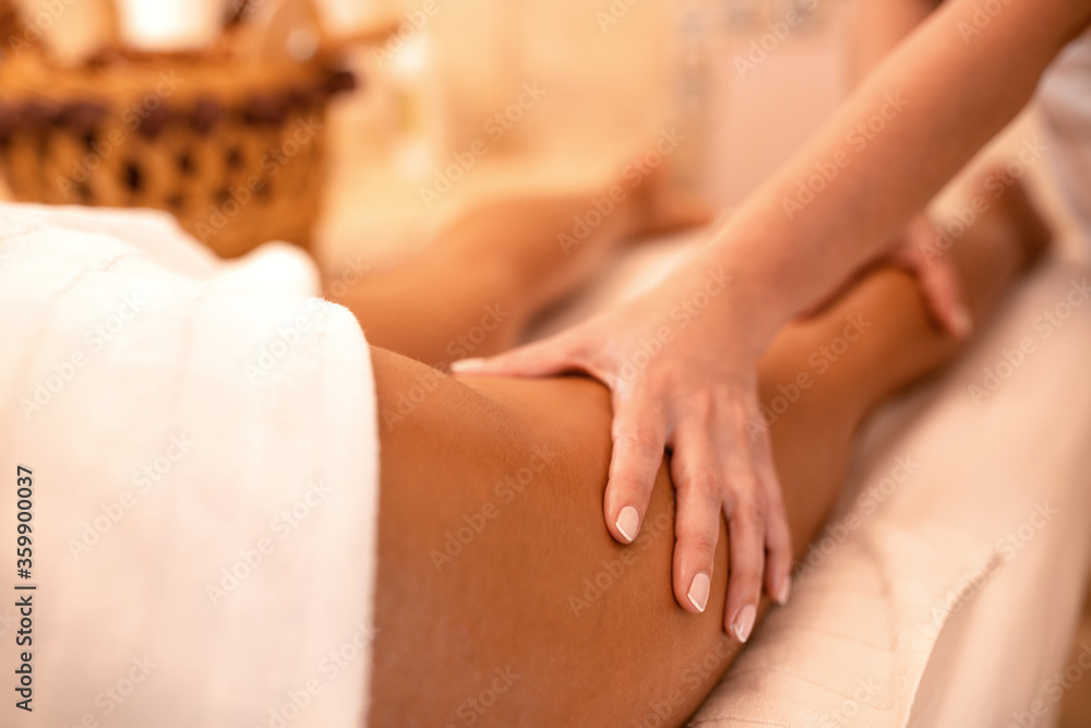 Fototapeta premium Experienced hands of a masseuse massaging upper thigh area