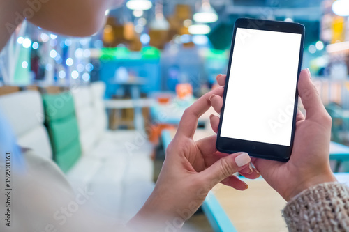 Mockup image: woman looking at black smartphone mobile device with blank white display at cafe, restaurant - close up view. Mock up, white screen, copyspace, template, isolated, technology concept