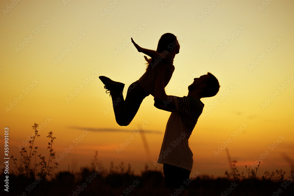 Silhouette of father throwing up his happy daughter in the air at sunset. family time togehter Silhouette of father throwing up his happy daughter in the air at sunset. family time togehter