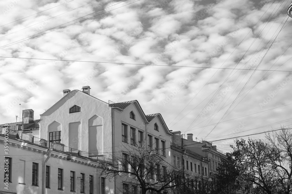 Black and white photo of beautiful building on the zig zag clouded sky background. Monochrome architecture photography.